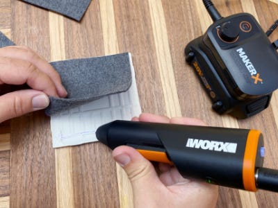 using mini glue gun to glue felt to bottom of coaster 