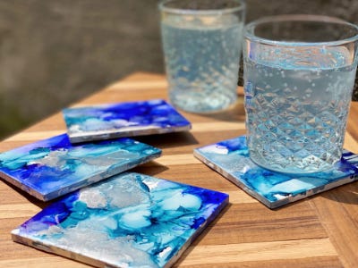 two drinks filled with liquid while one is on ink coaster