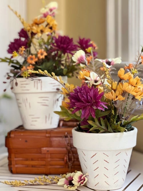 etched pots containing flowers by a window