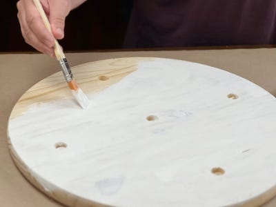 person painting the wooden round