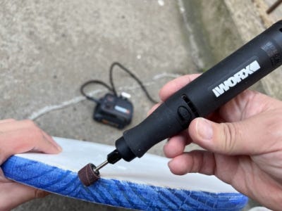 person using the rotoary tool to sand the wooden round