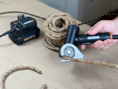 person using the rotary cutter to cut the rope