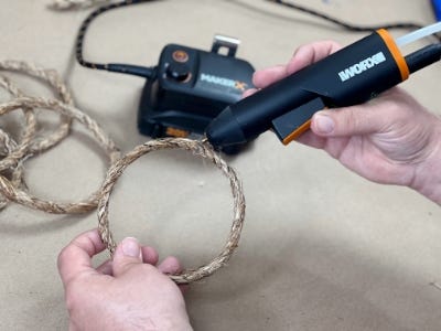 person using the hot glue gun on the rope