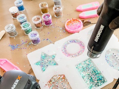 colorful sparkle and beaded resin designs being heated by heat gun