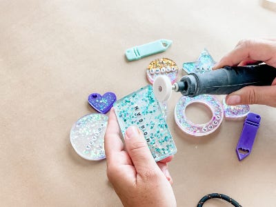 using rotary tool sanding down edges of square resin tag