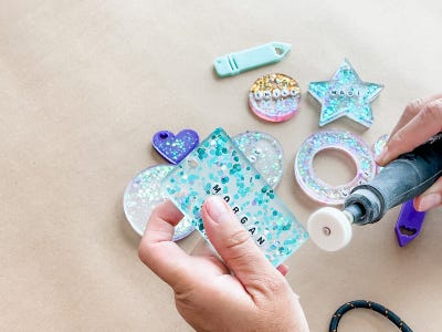 using rotary tool sanding down bottom edges of square resin tag