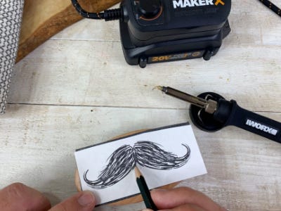 wood and metal laying next to a man drawing mustache