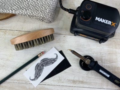 wood and metal and charger battery crafter laying next to mustache printing and beard brush