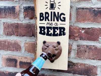 drink being opened by bear bottle opener hanging on brick wall