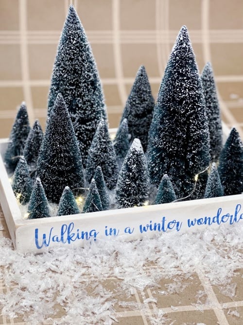 Bottle brush trees sitting on paper with artificial snow