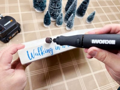 using rotary tool sander to sand down side of wood basket