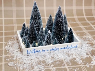 walking in winter wonderland chistmas tree tray with lights on and snow scattered around it