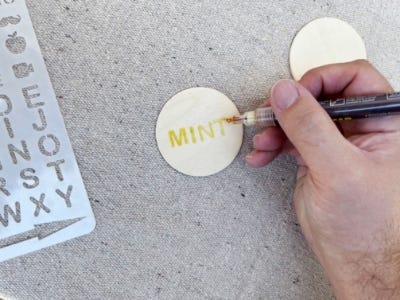 using pen to trace the word mint on to wood circle