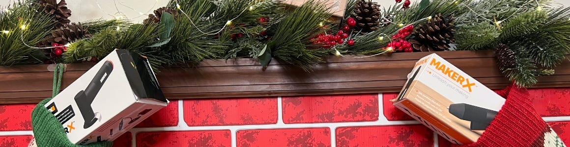 cardboard fireplace with greenery on top and presents hanging from it