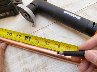 measuring tape measuring copper pipe next to worx grinder