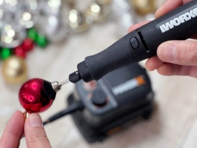 rotary tool being used on red ornament to have a rustic look with blurred background