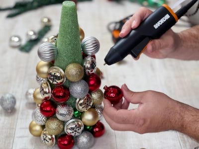 person gluing ornaments onto the foam cone