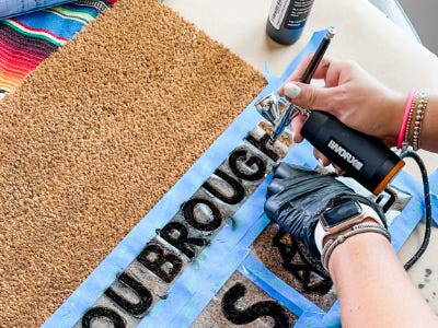 Using airbush to paint words onto doormat