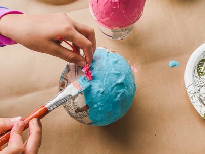 Using paint brush to paint blue color on top newspaper stripped ballon