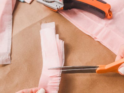 Pink color stripped tissues being cut by scissors 