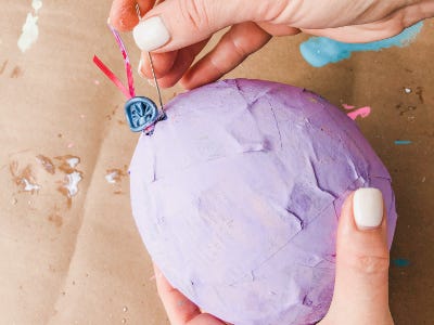 Hand holding purple ballon holding needle popping the ballon