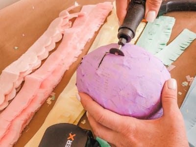 Rotary tool cutting square into pink harded ballon case