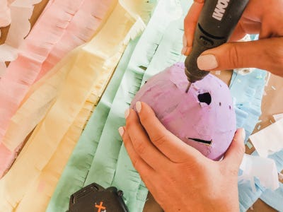 Rotary tool drilling holes into top of hard cased ballon shell