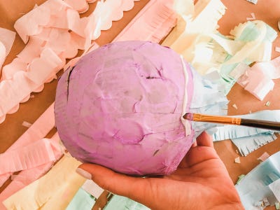 Painting on tacky glue into holes into top of hard cased ballon shell
