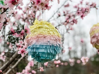 Colorful easter egg pinata hanging from pink flower tree