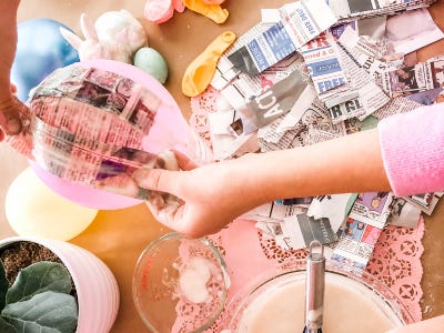 Wet stripped newspaper being applied to pink ballon