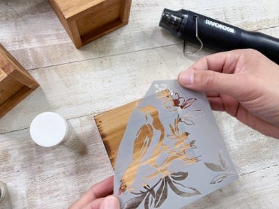 applying stencil to side of wood box