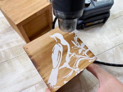 using heat gun to melt powder onto glue to wood piece