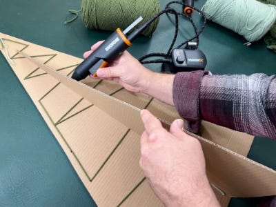 using mini glue gun to glue two card board pices together as a stand