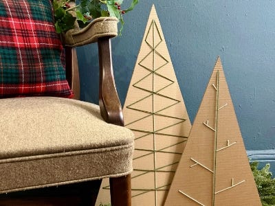 two cardboard christmas trees standing next to chair