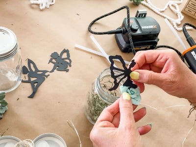 fairy being glued to lights above mason jar