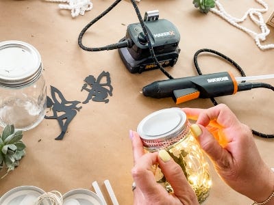 holding lighted jar in front of hot glue gun