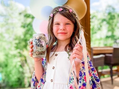 girl holding mason jar with lights and fairy inside