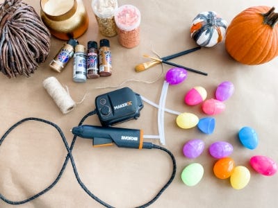 hot glue gun next to decorative colorful eggs and pumpkin