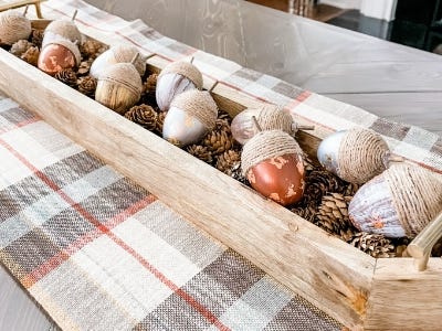 multiple twine decorative acorns laying in wooden basket