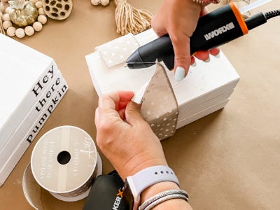 hot glue gun glueing ribbon and three stacked wood blocks