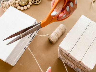 cutting yarn with scissors over 3 stacked wood blocks