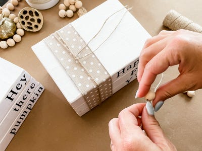 threading beads onto yarn thread over the three faux stacked wood blocks