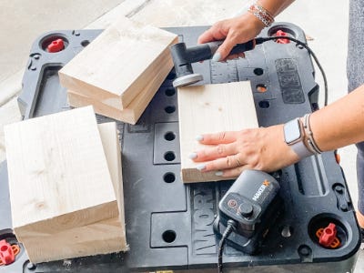 using grinder tool to grind down the corners of wood block thats on worx table 