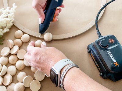 using mini glue gun to glue balls too wreath frame