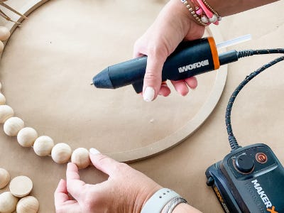 using mini glue gun to glue multiple wooden balls too wreath frame