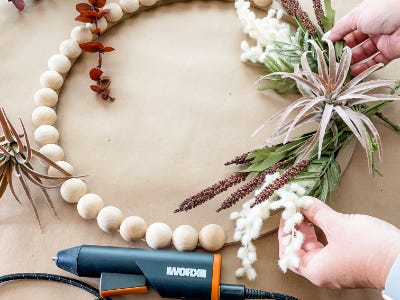 holding greenery above wooden wreath frame