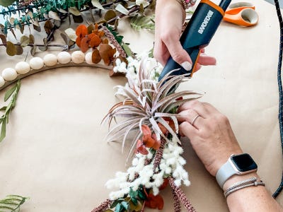 applying greenery to wooden wreath frame