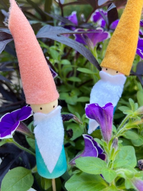 Garden gnome plant stakes displayed in garden.