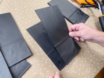 Placing two black tissue paper together that have glue on them