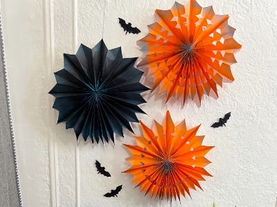 Orange and black pin wheel hanging on wall with little bats glued on too